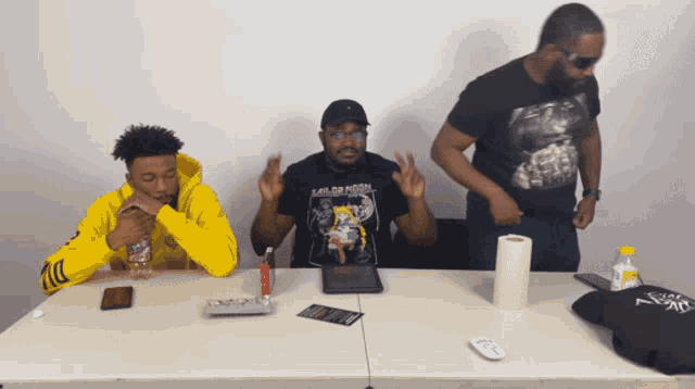 a man wearing a shirt that says sailor moon is sitting at a table