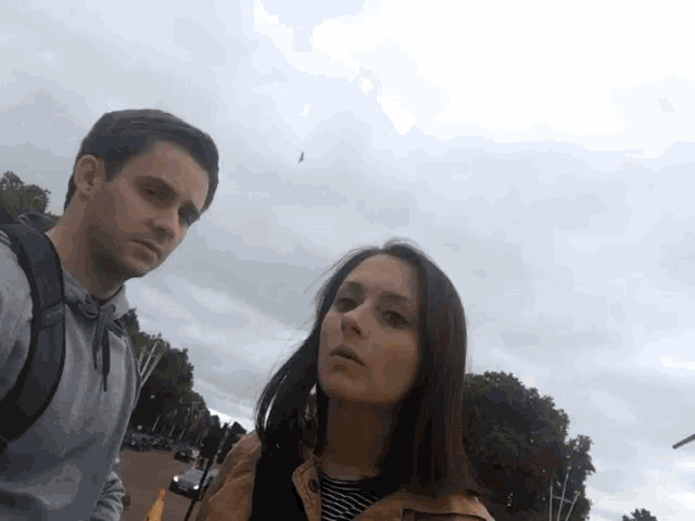 a man and a woman are posing for a picture with a bird in the background