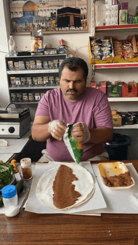 a man in a purple shirt is preparing food in front of a display of cigarettes