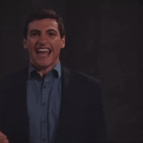 a man in a suit and a blue shirt smiles