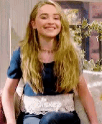 a young girl is sitting on a couch wearing a disney shirt