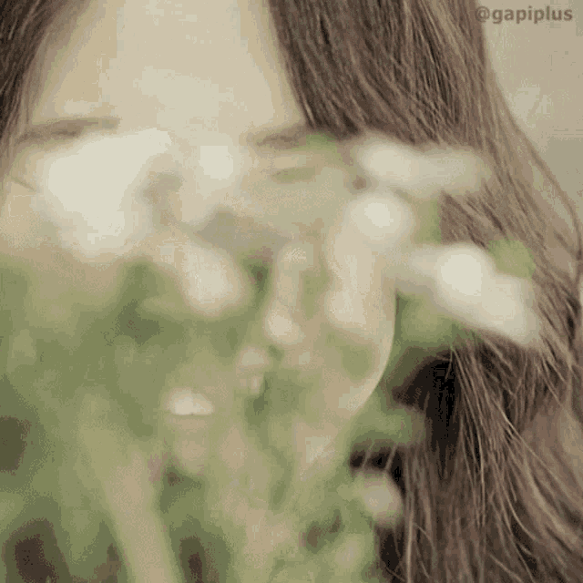 a woman covering her face with flowers with gapiplus written on the bottom