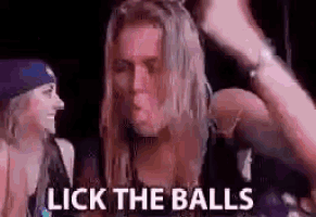 a man with long hair is licking a woman 's balls while a woman looks on .