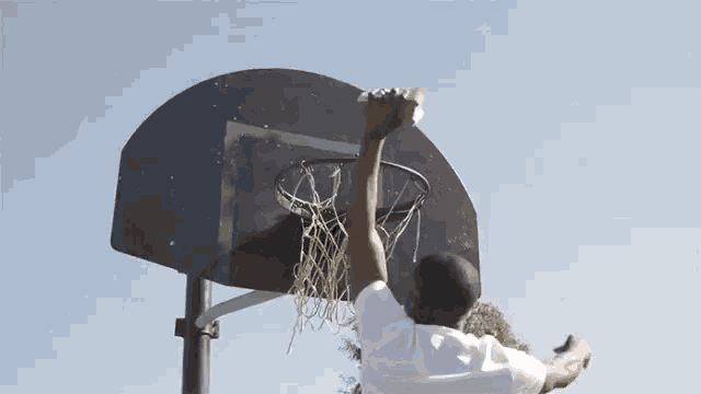 a man in a white shirt is dunking a basketball in a hoop