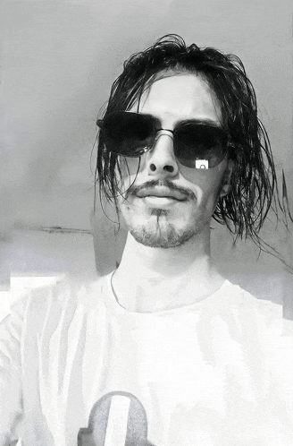 a man with a beard wearing sunglasses and a white shirt with the letter l on it
