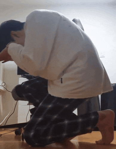 a person kneeling down with a white shirt that has the letter t on it