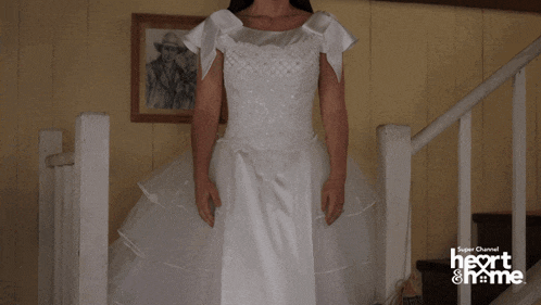 a woman in a white wedding dress is standing on a set of stairs with a super channel heart & home logo