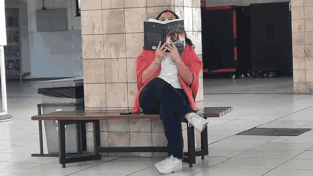 a woman is sitting on a bench reading a book called ' a brief history of time '