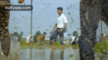 a man in a white shirt is standing in a puddle of water surrounded by people .