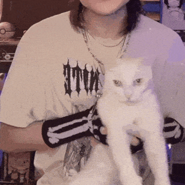 a person holding a white cat wearing a shirt that says kill on it