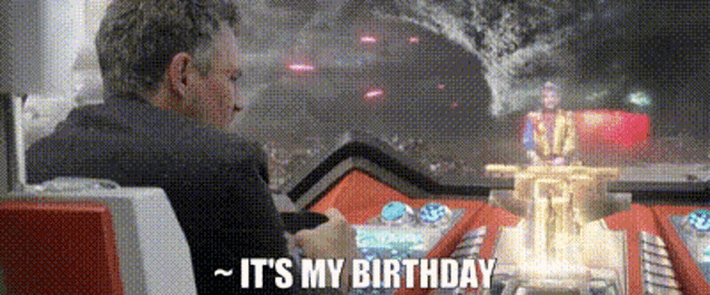 a man is sitting in a chair with the words `` it 's my birthday '' written on the screen .