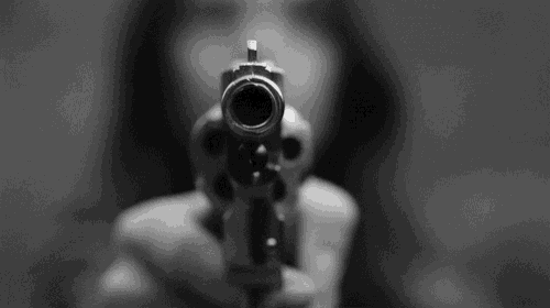 a person is pointing a gun at the camera in a black and white photo