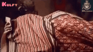 a woman in a striped shirt is laying on the floor holding a cell phone .