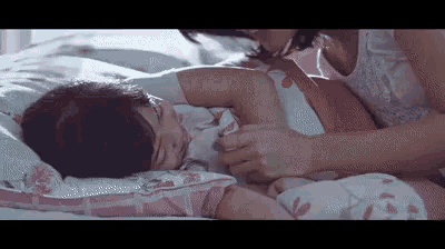 a woman is laying on a bed with a little girl and petting her .