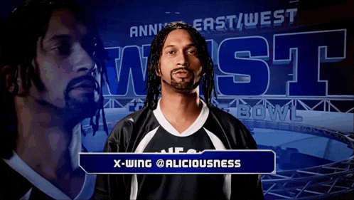 a man with dreadlocks and a beard stands in front of a sign that says x-wing @aliciousness