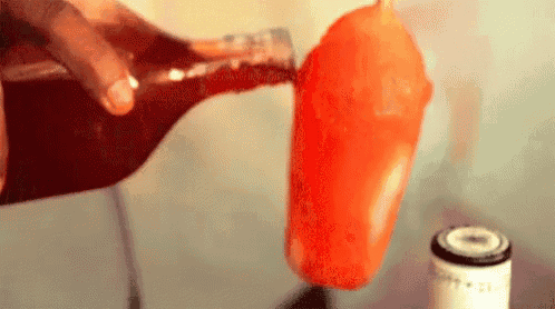 a bottle of soda is being poured into a popsicle on a stick