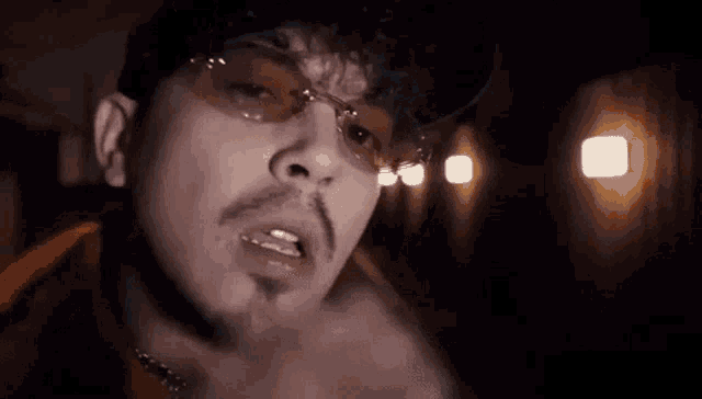 a man wearing glasses and a hat is smoking a cigarette in a dark room .