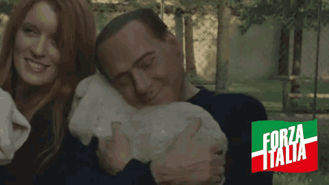 a man and woman holding a baby rabbit with forza italia written on the bottom right