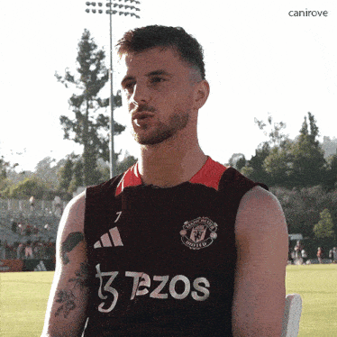 a man wearing a manchester united jersey is sitting in a chair
