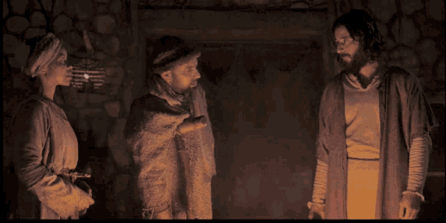 a man and a woman are standing next to each other in front of a fireplace