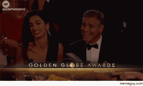 a man in a tuxedo and a woman in a dress are sitting at a table at the golden globe awards