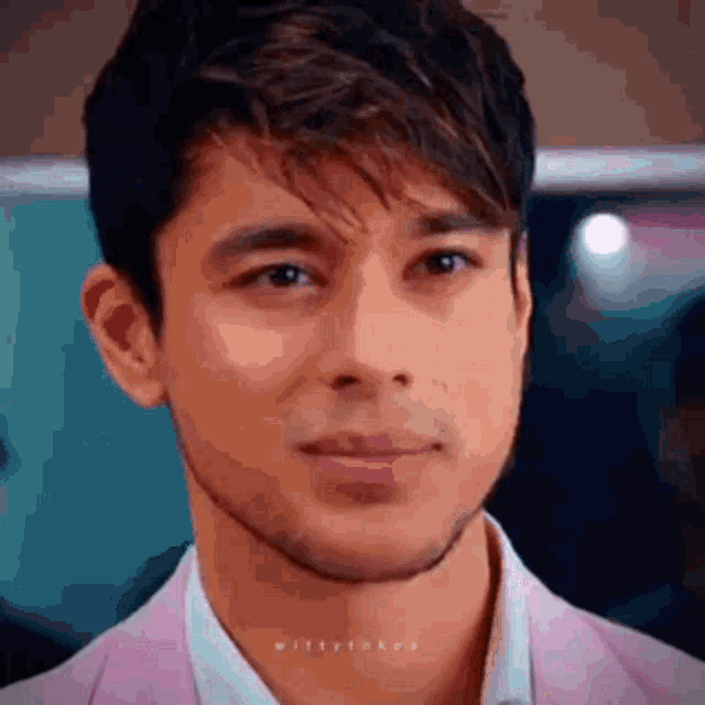 a close up of a man 's face in a pink suit and white shirt .