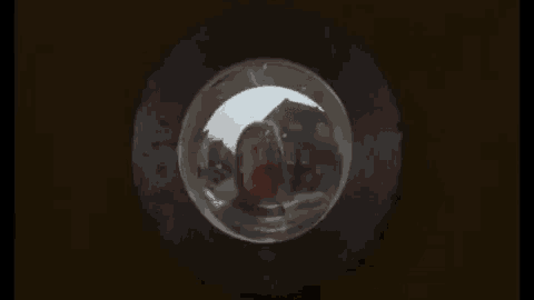 a man is looking through a peephole into a glass ball .