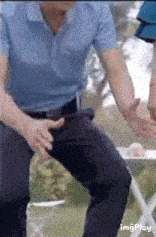 a man in a blue shirt and black pants is sitting on a folding table .