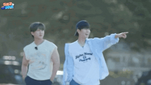 two men are standing next to each other and one is pointing at something .
