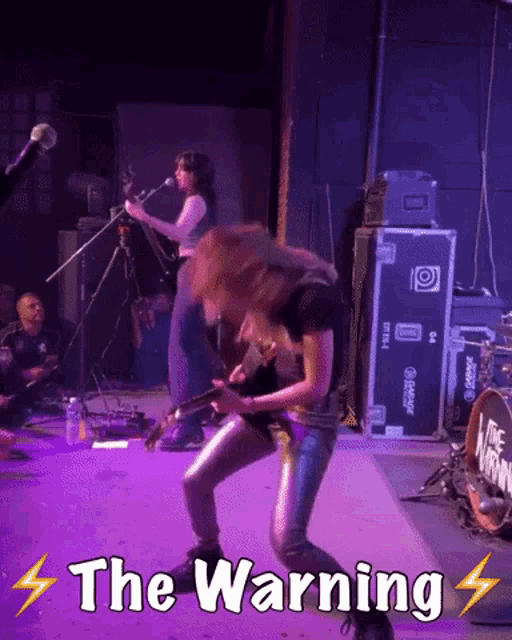 a woman playing a guitar in front of a sign that says the warning on it