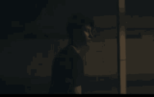 a man in a black shirt is standing in the dark looking at something .