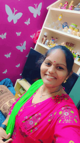 a woman is taking a selfie in front of a pink wall with butterflies painted on it