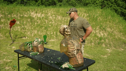 a man wearing a t-shirt that says left behind stands in front of a table with a skeleton on it