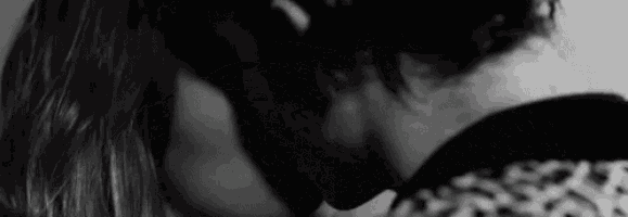 a black and white photo of a man and woman kissing each other .