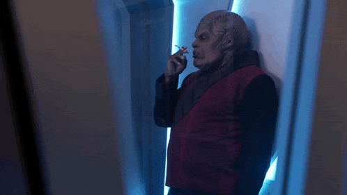 a man in a red vest is smoking a cigarette
