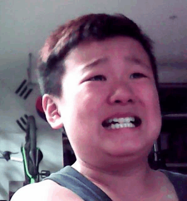 a young boy is crying and making a funny face with his mouth open .