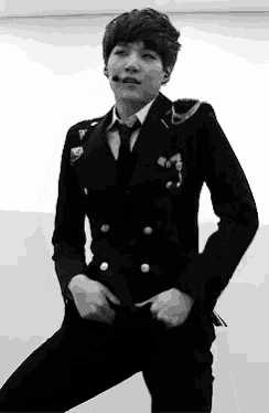 a black and white photo of a young man in a suit and tie dancing .
