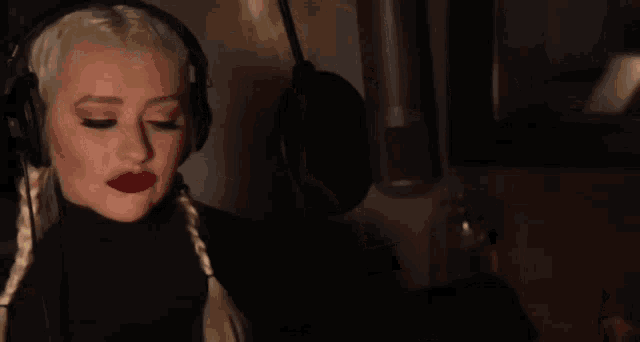 a woman wearing headphones is singing into a microphone in a dark room