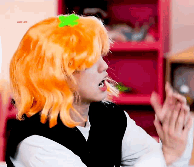 a man wearing an orange wig with a green flower on it .