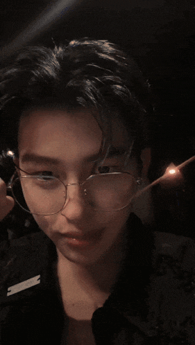 a young man wearing glasses and a ring on his finger takes a picture of himself