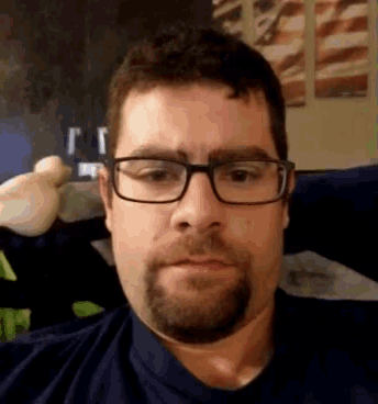 a man with glasses and a beard is sitting on a couch