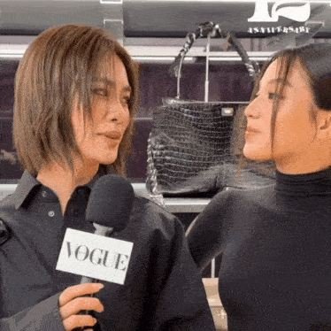 two women standing next to each other with a microphone that says vogue on it