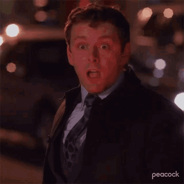 a man in a suit and tie is making a surprised face while walking down a street .