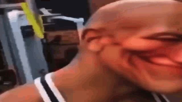a bald man is smiling in a gym while wearing a tank top .