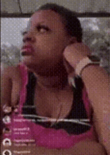 a woman in a pink tank top is sitting in a chair with her hands on her face .