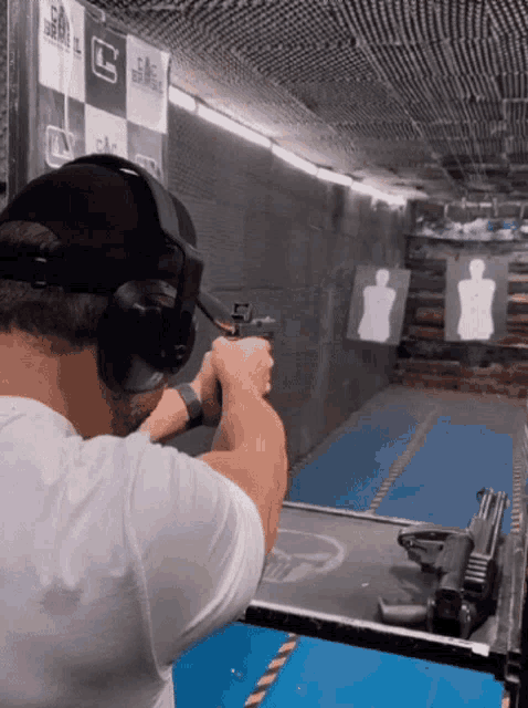 a man wearing headphones is shooting a gun at a target that says gmc