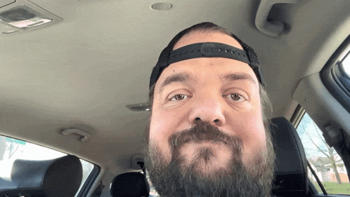 a man with a beard is sitting in a car