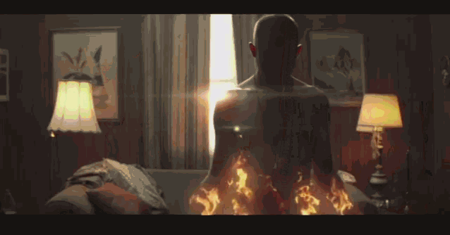 a man is sitting on a couch with flames coming out of his body