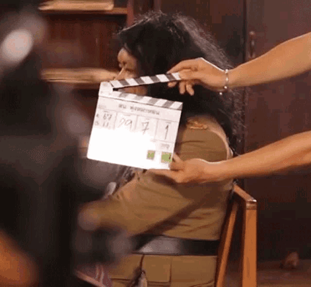 a person is holding a clapper board over a person 's face .