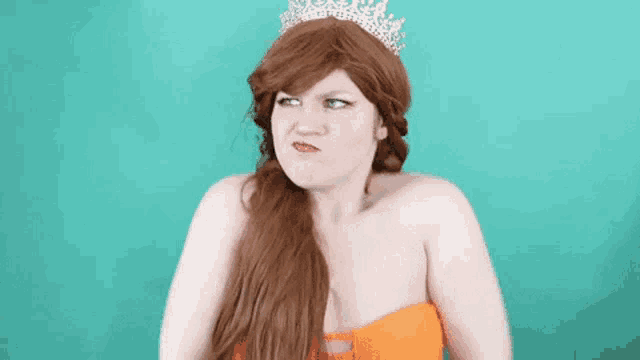 the woman is wearing a tiara and making a funny face .